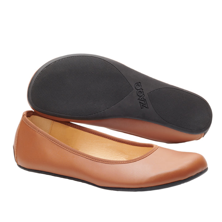 Wir präsentieren den QARMA Vegan Cognac von ZAQQ: Diese braunen Ballerinas zeichnen sich durch eine abgerundete Zehenpartie aus. Ein Schuh ist aufrecht und der andere umgedreht zu sehen, wodurch die schwarze Sohle hervorgehoben wird. Die glatte Oberfläche und das glatte Design dieser Ballerinas sorgen für Komfort beim täglichen Tragen.