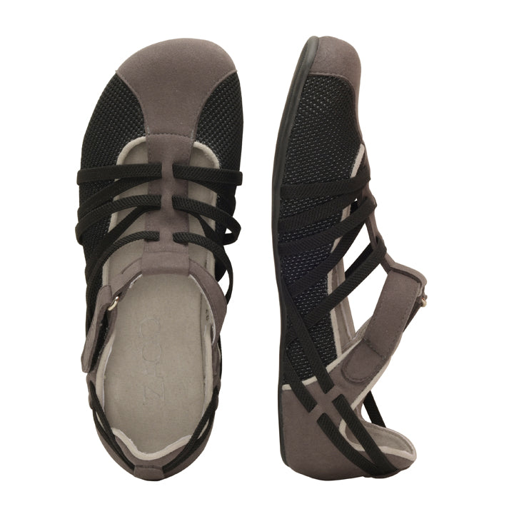 Die QLAIRE Dark Grey Sandalen von ZAQQ zeichnen sich durch ein Riemchendesign mit praktischen Klettverschlüssen aus. Eine Sandale ist von der Seite abgebildet, während die andere von oben präsentiert wird, wodurch das atmungsaktive Mesh-Material und der minimalistische Stil, der an einen Barfußschuh erinnert, hervorgehoben werden.