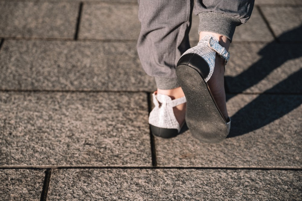 CLIQ Silver-Sandalen von ZAQQ mit silbernem Metallic-Finish, offenen Zehen, Knöchelriemen und einer Kautschuksohle auf weißem Hintergrund.