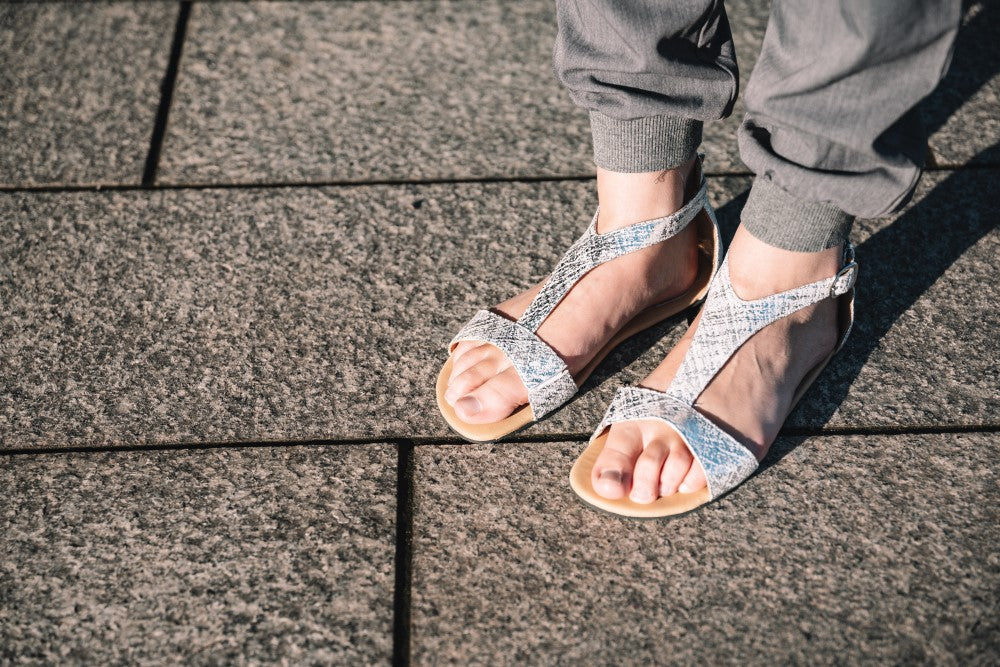 CLIQ Silver-Sandalen von ZAQQ mit silbernem Metallic-Finish, offenen Zehen, Knöchelriemen und einer Kautschuksohle auf weißem Hintergrund.