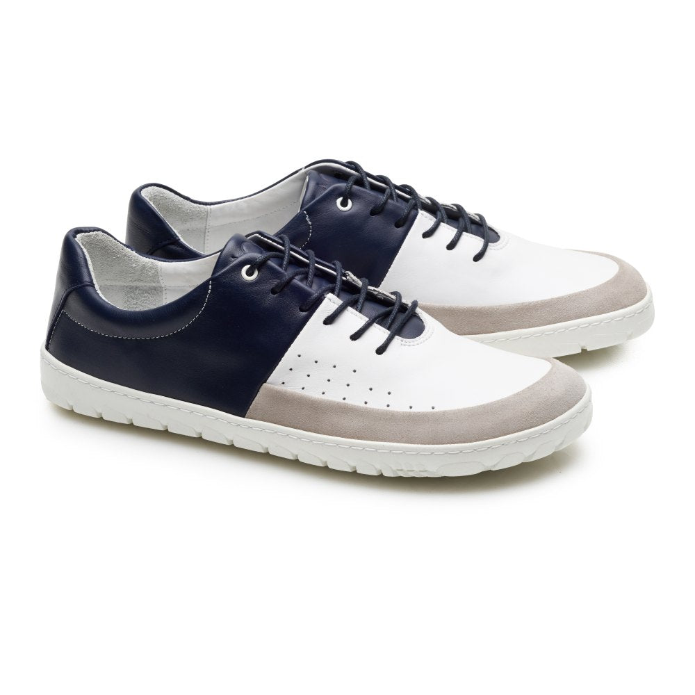 Der QOOL Navy von ZAQQ ist ein lässiger Barfuß-Sneaker, der in Weiß, Marineblau und Beige erhältlich ist. Diese aus Nappaleder gefertigten Sneaker verfügen über weiße Sohlen und Schnürsenkel mit perforierten Details an den Seiten für außergewöhnlichen Tragekomfort. Sie werden vor einem weißen Hintergrund stilvoll in Szene gesetzt.