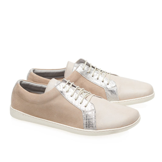 Wir präsentieren die QORE Low Silver-Sneaker von ZAQQ, ein stilvolles Paar beige Schuhe mit metallischen Silberakzenten an den Seiten. Diese bequemen Sneaker haben weiße Sohlen und Schnürsenkel und bieten ein elegantes Finish, das ihren schlanken und modernen Look vor einem schlichten weißen Hintergrund unterstreicht.