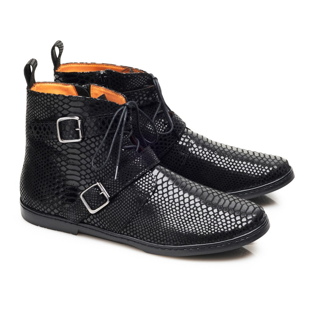 Wir präsentieren den Quail Ridge Black von ZAQQ: ein Paar stylische schwarze Stiefeletten aus strukturiertem Leder mit Schlangenmuster, mit silbernen Schnallen und schwarzen Schnürsenkeln. Das Innere weist ein kontrastierendes orangefarbenes Futter auf. Diese Stiefel strahlen die Eleganz von Chelsea Boots aus und werden vor einem schlichten weißen Hintergrund präsentiert.