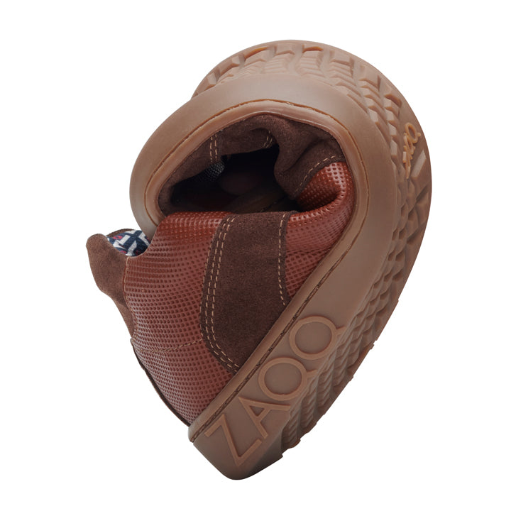 Der RIQO Brown von ZAQQ ist ein flexibler Schuh, der sich zusammenrollt, um seinen außergewöhnlichen Komfort zu zeigen. Er verfügt über strukturierte Sohlen und den seitlich aufgedruckten Markennamen, was sowohl Stil als auch Tragekomfort gewährleistet.