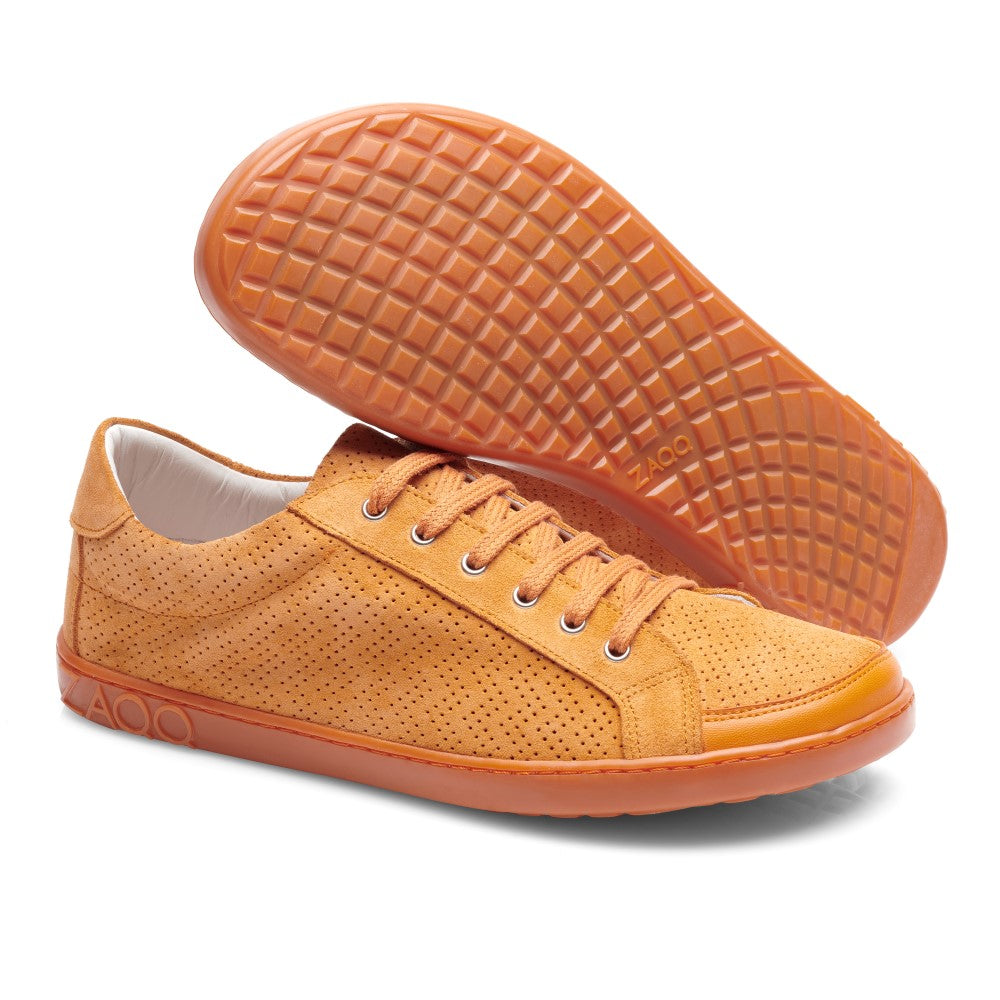 Ein Paar SLOQ Orange Sneaker von ZAQQ in einem warmen Orangeton mit perforierten Details und Veloursleder-Finish. Ein Schuh steht aufrecht und betont sein Seitenprofil, während der andere seine strukturierte Sohle und Schnürsenkel zeigt. Das sportlich-lässige Design wird durch die flexible Kautschuksohle ergänzt.