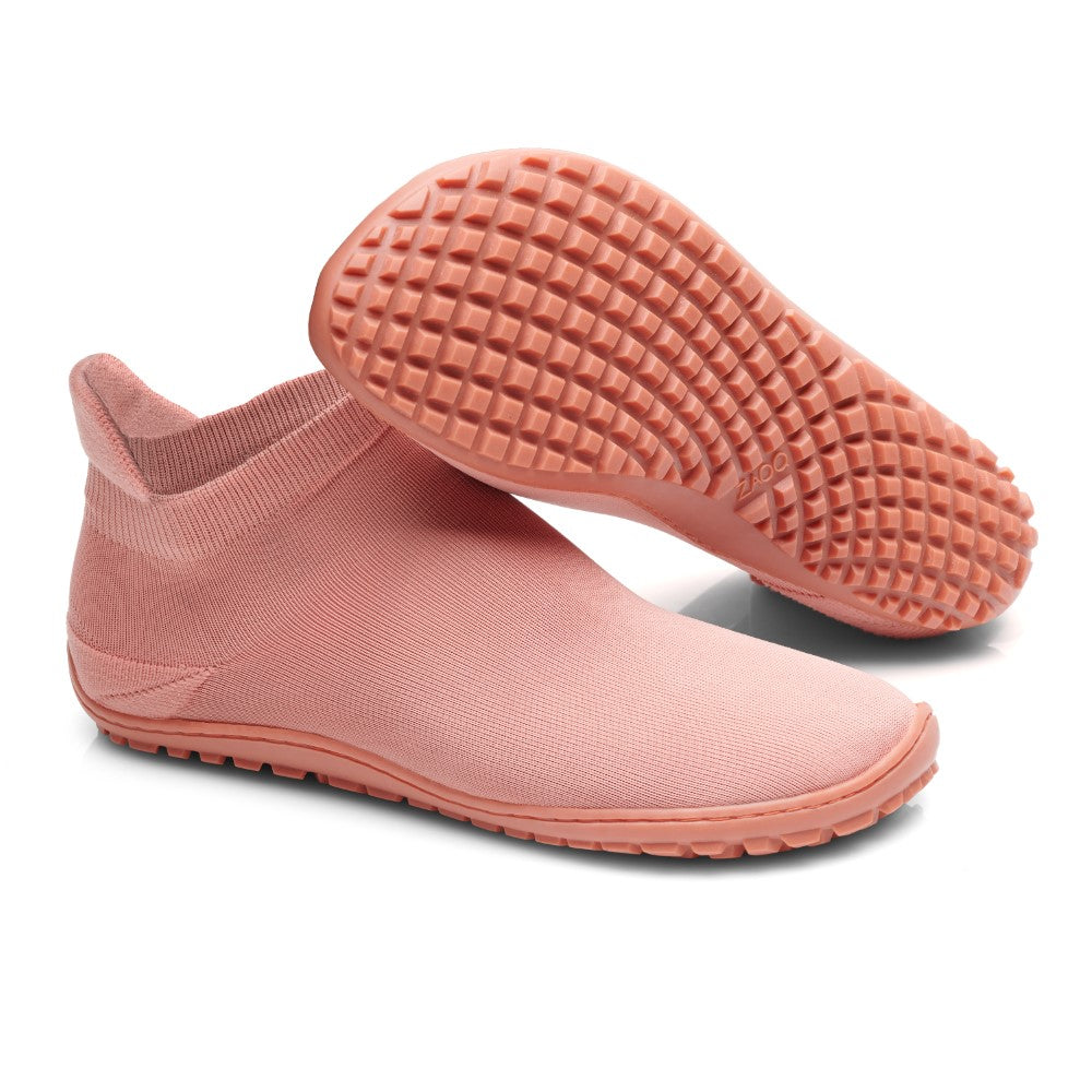 Wir präsentieren den SOQQ Living Coral von ZAQQ: ein stilvolles Paar rosa Slipper aus knöchelhohem Stoff, die sowohl von oben als auch von unten zu sehen sind. Das gitterartige Muster auf der strukturierten Sohle sorgt für hervorragenden Halt und bietet die für Barfußschuh-Designs typische Flexibilität.