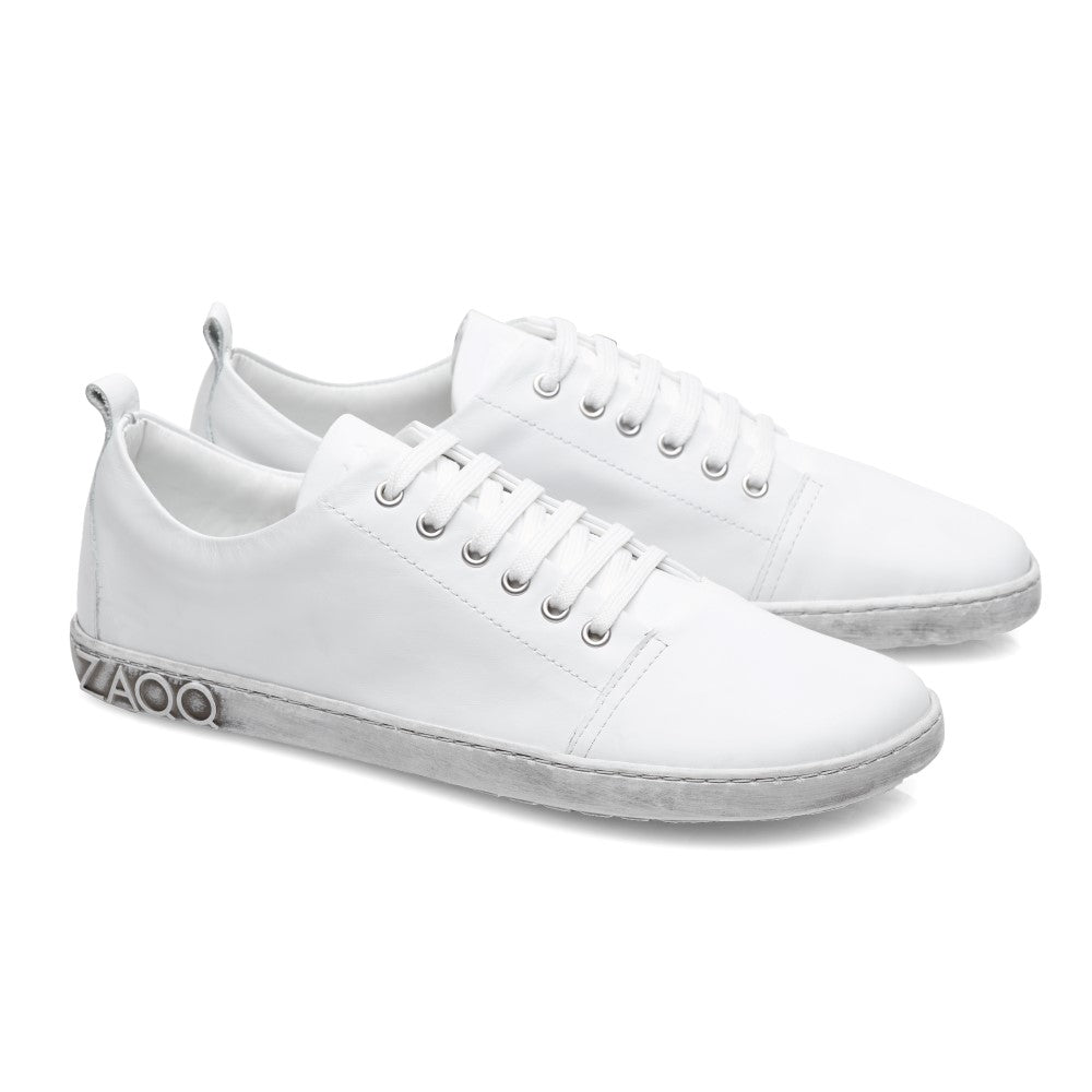 Der ZAQQ TAQQ Nappa White Sneaker ist ein weißer Low-Top mit Schnürung aus Nappaleder, im minimalistischen Design mit silbernen Metallic-Akzenten an der Seitensohle und einer flexiblen Kautschuksohle für hohen Tragekomfort.